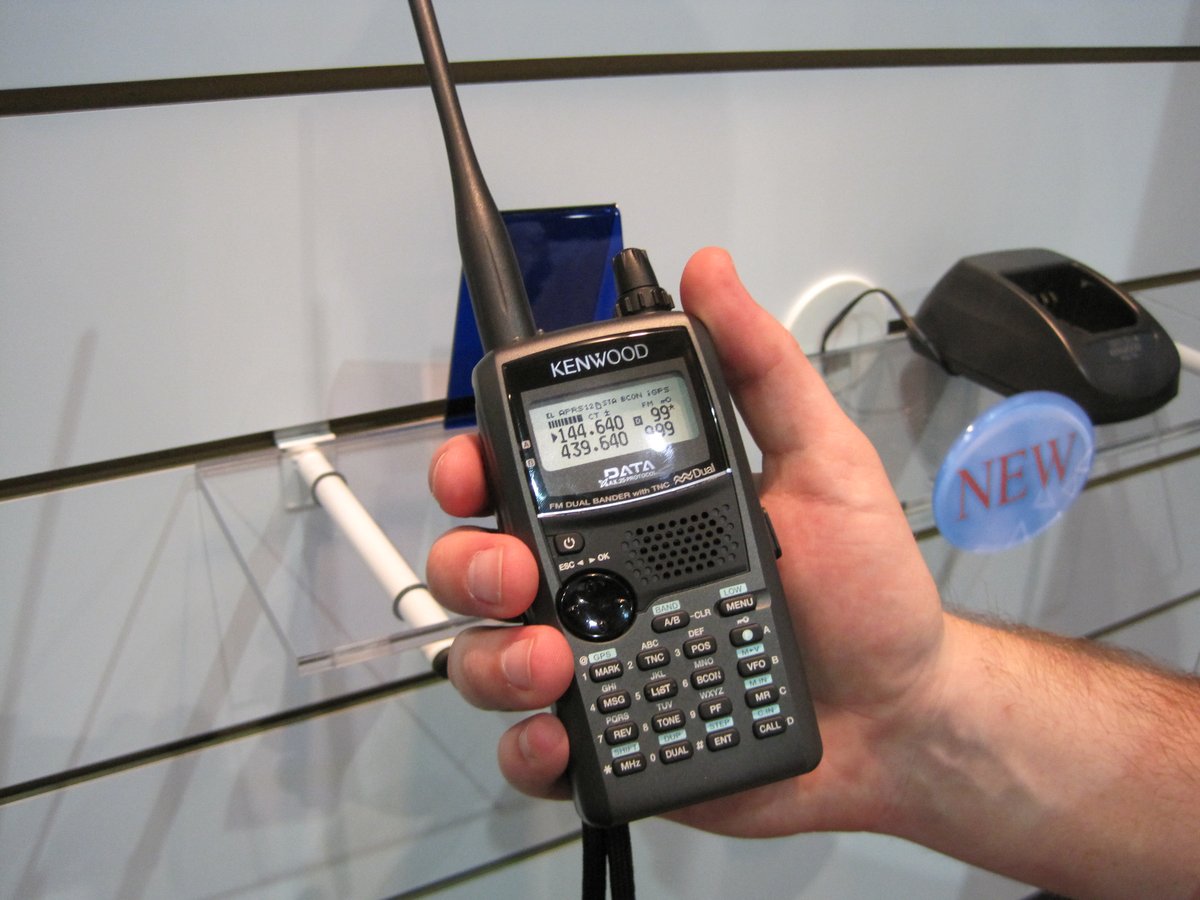 A dual-band handheld radio held up against the sky